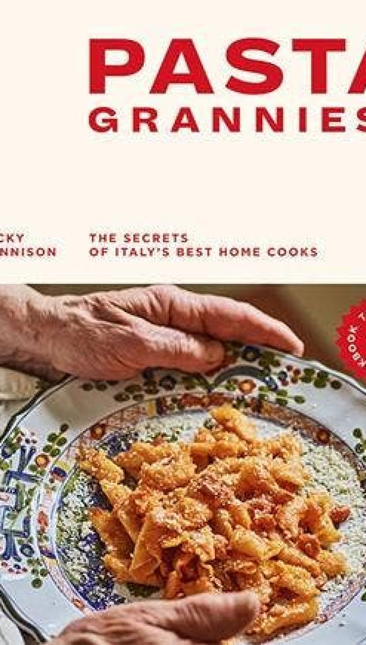 Ceramic plate with pasta and grated cheese, colorful patterned design on white background