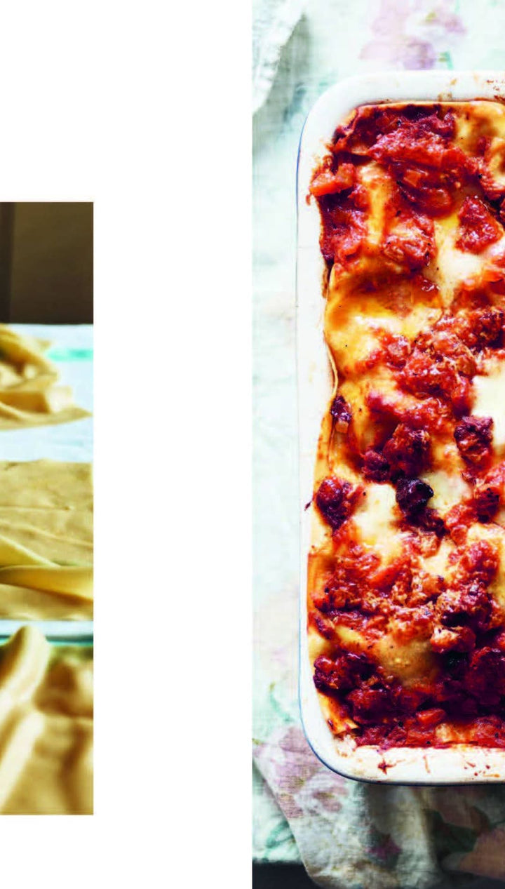 Lasagna pan with baked pasta and tomato sauce, browned edges, white ceramic material.