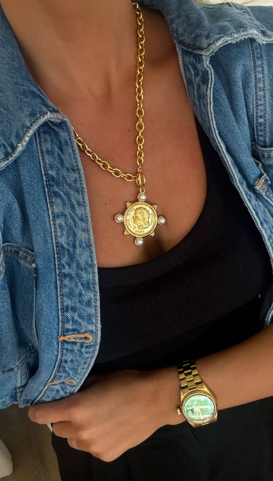 Gold chain necklace with a circular medallion pendant featuring an engraved portrait, surrounded by six small pearls and set on a gold-toned clasp.