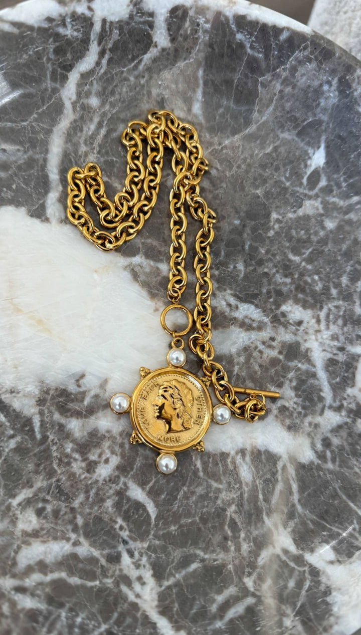 Gold-toned coin pendant necklace with a classic chain, adorned with four small pearls and featuring an engraved profile design.