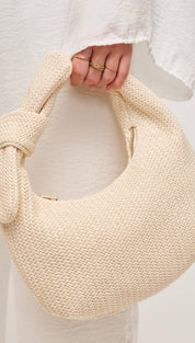 Knot-handled, woven, crescent-shaped handbag.