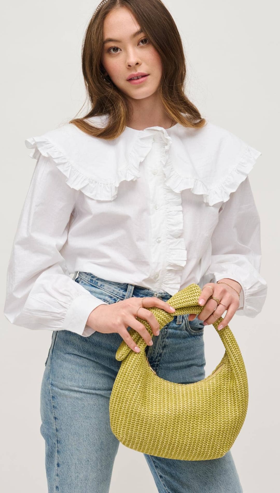 Woman holding a yellow woven handbag.