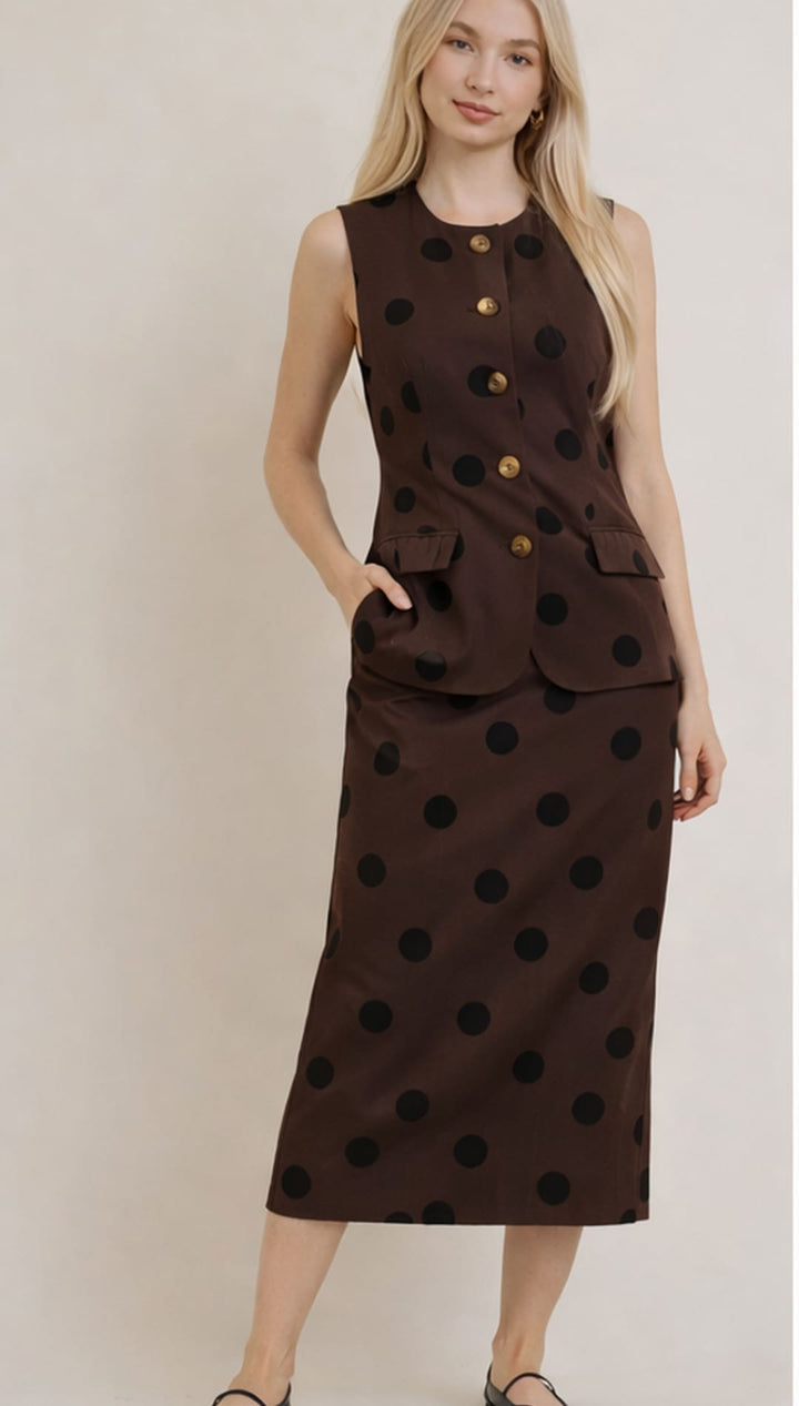 A brown sleeveless dress with black polka dots and gold buttons.