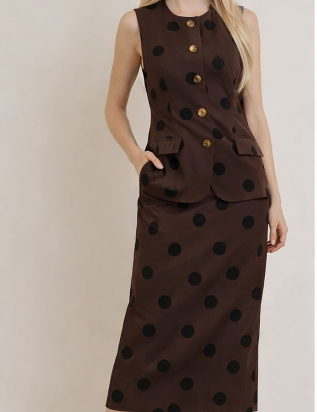 A brown sleeveless dress with black polka dots and gold buttons.