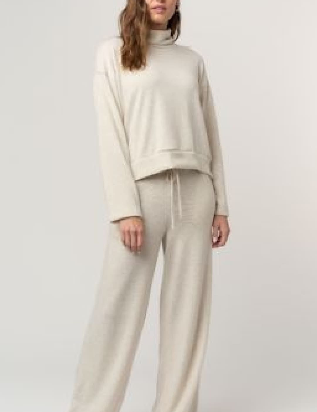 Beige turtleneck sweatshirt and matching wide-leg pants set.