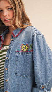 Blue denim shirt with colorful embroidered citrus design on the chest pocket and red stitching along the collar.
