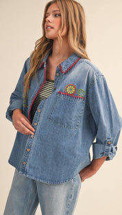 Blue denim button-up shirt with colorful embroidered fruit and leaf designs on the collar, placket, and pocket.