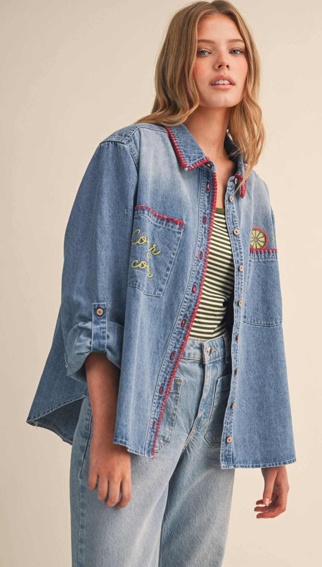 Light-wash denim shirt with red and yellow embroidery on the collar, pockets, and sleeves.