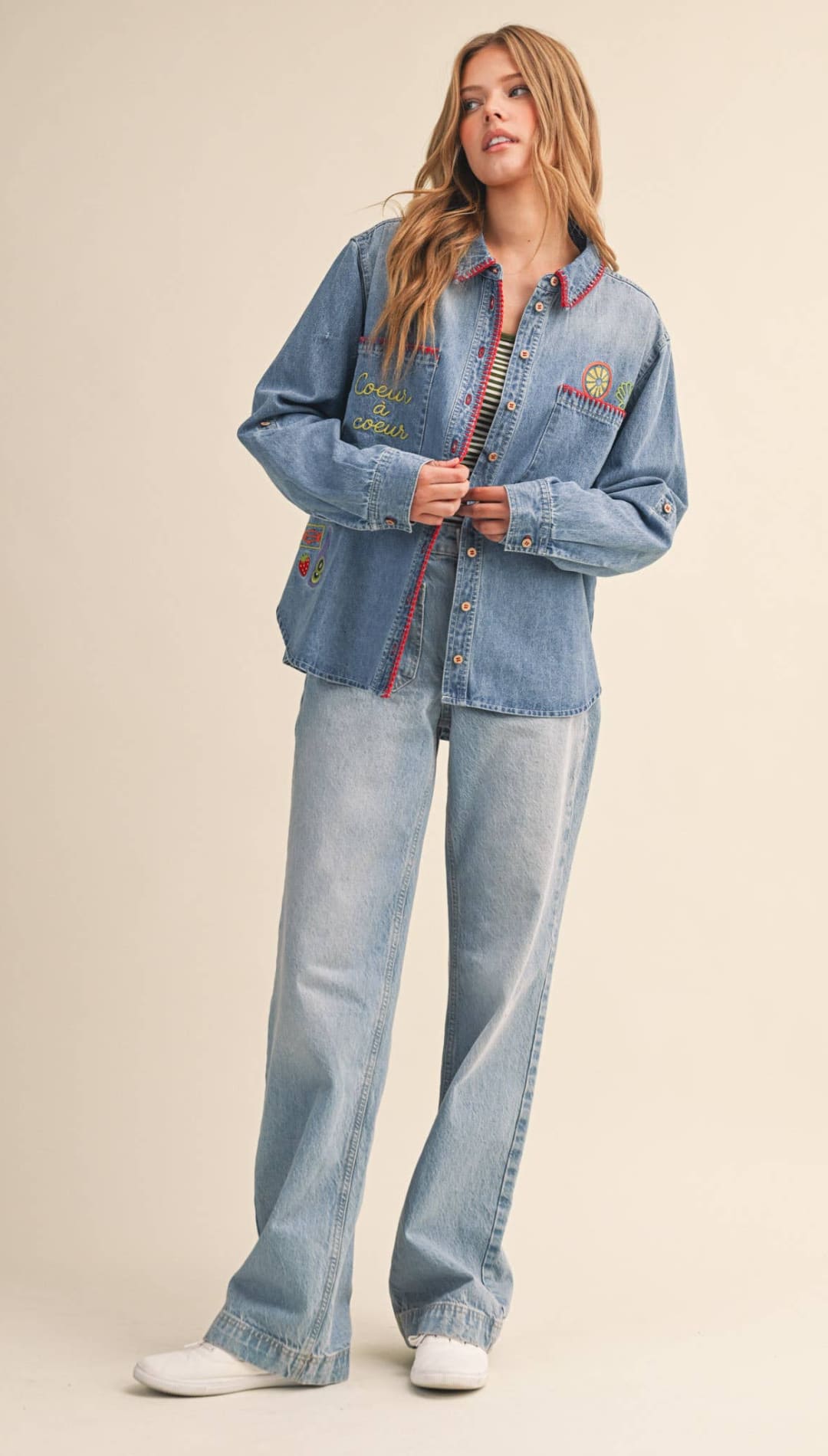 Light-wash denim button-up shirt with colorful embroidered patches and a striped inner lining.
