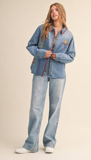Light-wash denim button-up shirt with colorful embroidered patches and a striped inner lining.