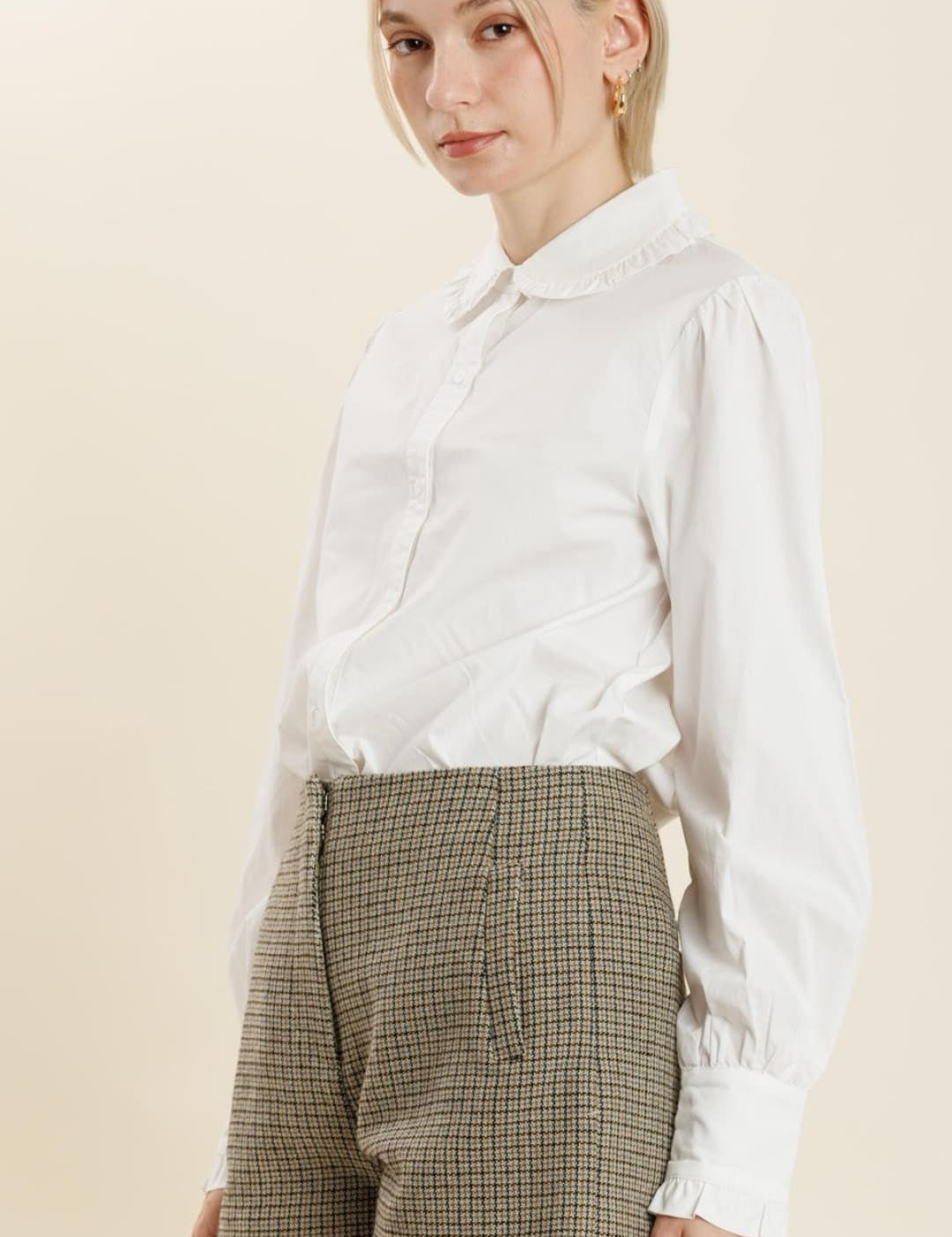 A woman’s white long-sleeved collared shirt with brown checkered shorts.