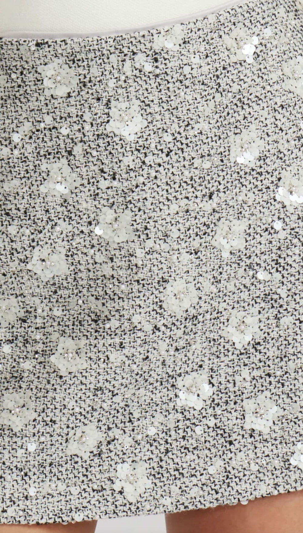 Silver sequin mini skirt with floral pattern and cutout hem.