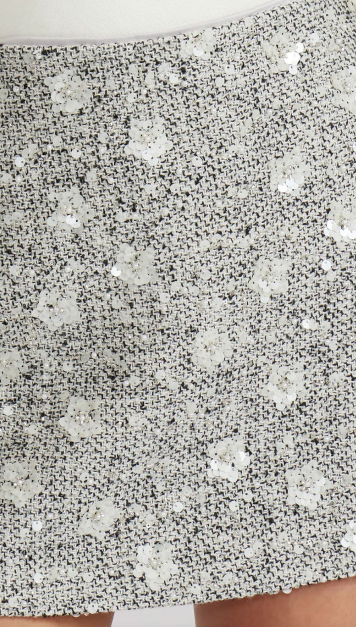 Silver sequin mini skirt with floral pattern and cutout hem.