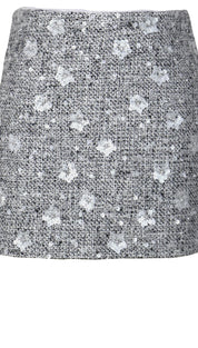 Tweed mini skirt with silver sequins and floral pattern, gray background.