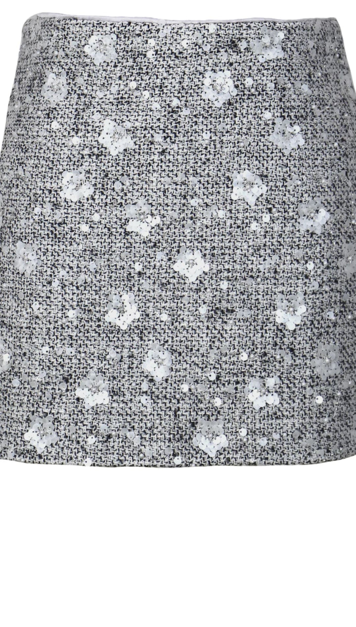Tweed mini skirt with silver sequins and floral pattern, gray background.