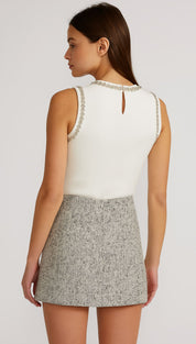 White sleeveless top with silver embellishments and gray tweed mini skirt.