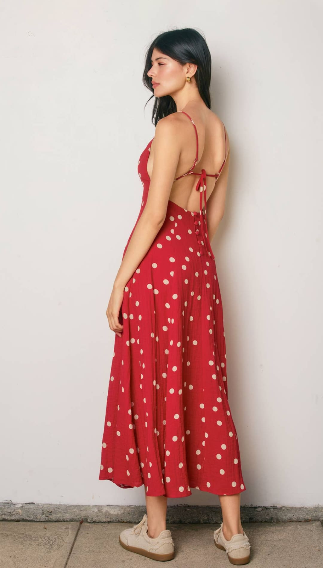 A red midi dress with white polka dots and thin spaghetti straps, featuring a back tie detail.