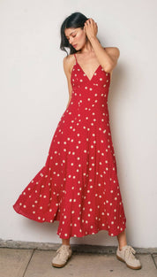 A flowing red midi dress with white polka dots and thin spaghetti straps.