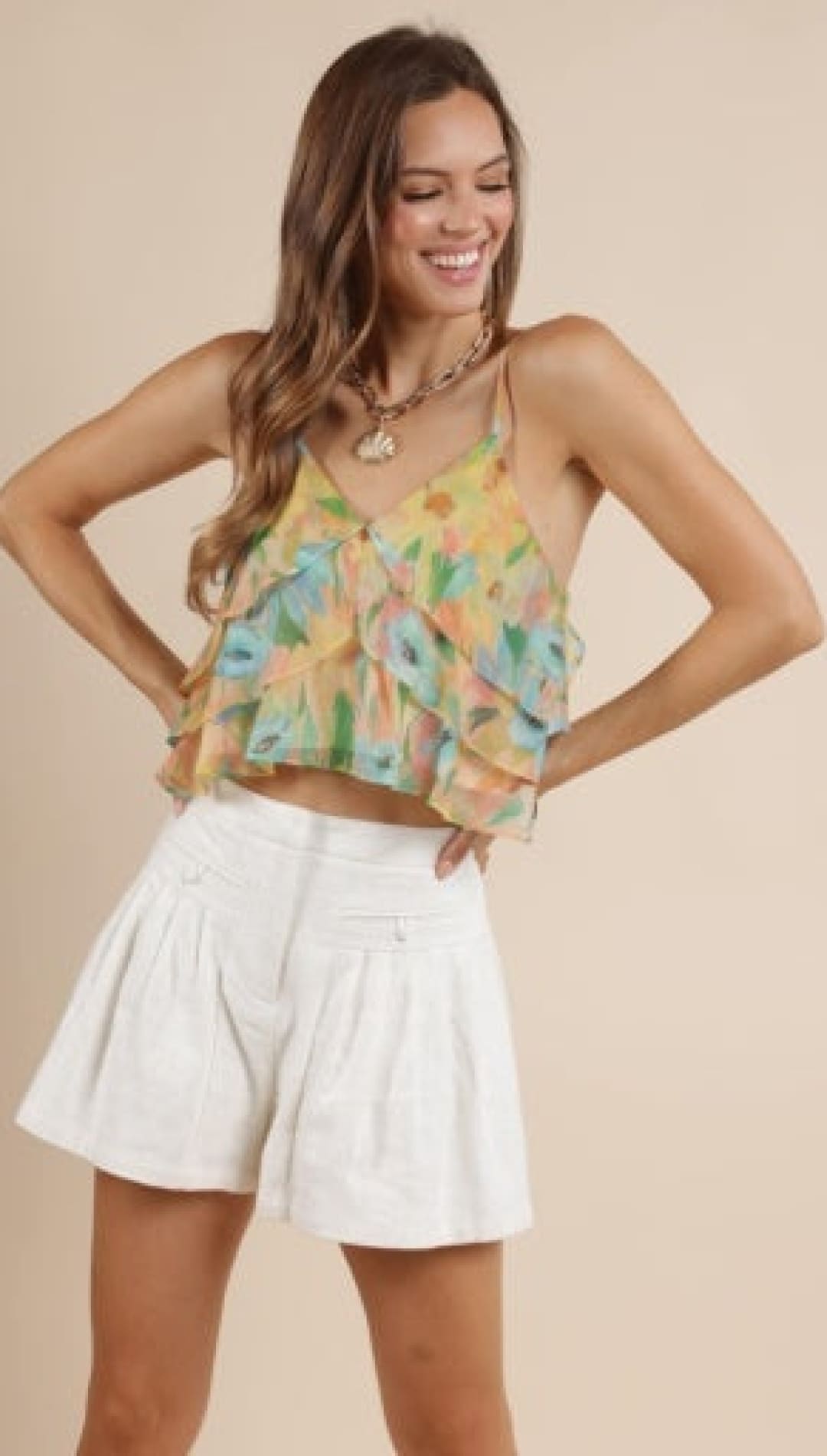 Woman in a colorful ruffled top and white shorts.