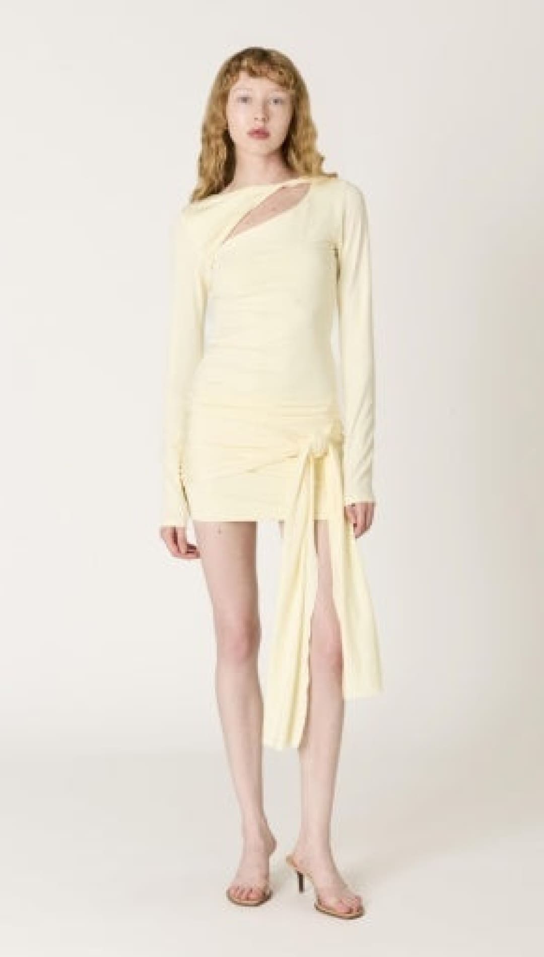 A pale yellow, long-sleeved mini dress with a draped asymmetrical neckline and side slit.