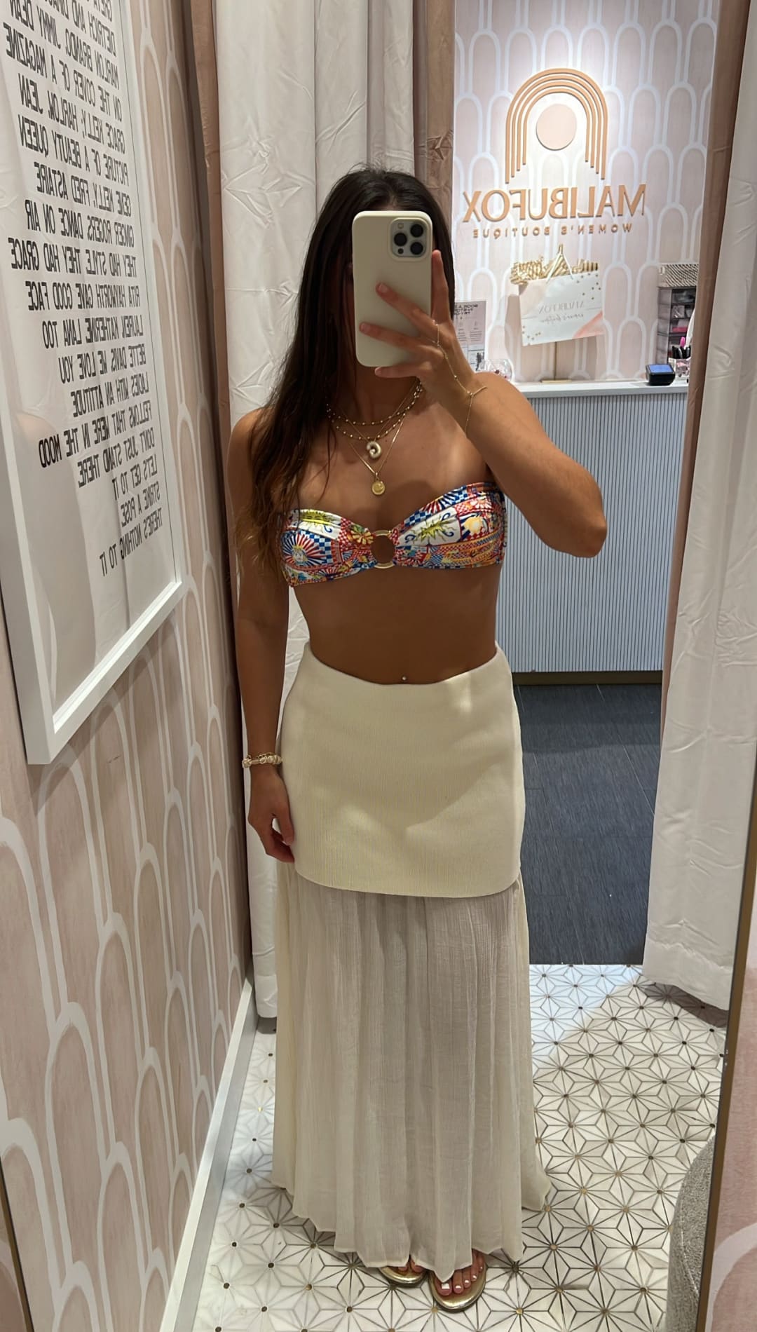 Woman in colorful bikini top and white skirt.