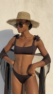 Woman in a black bikini with a straw hat and sunglasses.