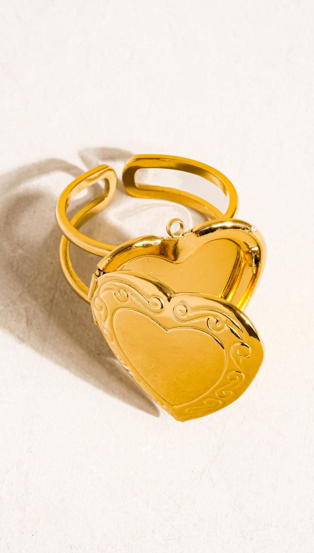 Gold-toned heart-shaped locket ring with ornate scrollwork detailing and a hinged design.