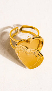 Gold-toned heart-shaped locket ring with ornate scrollwork detailing and a hinged design.