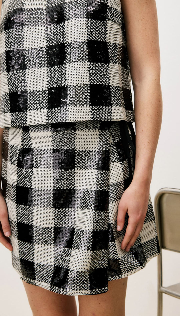 Black and white plaid skirt with ruffled hem, textured fabric.