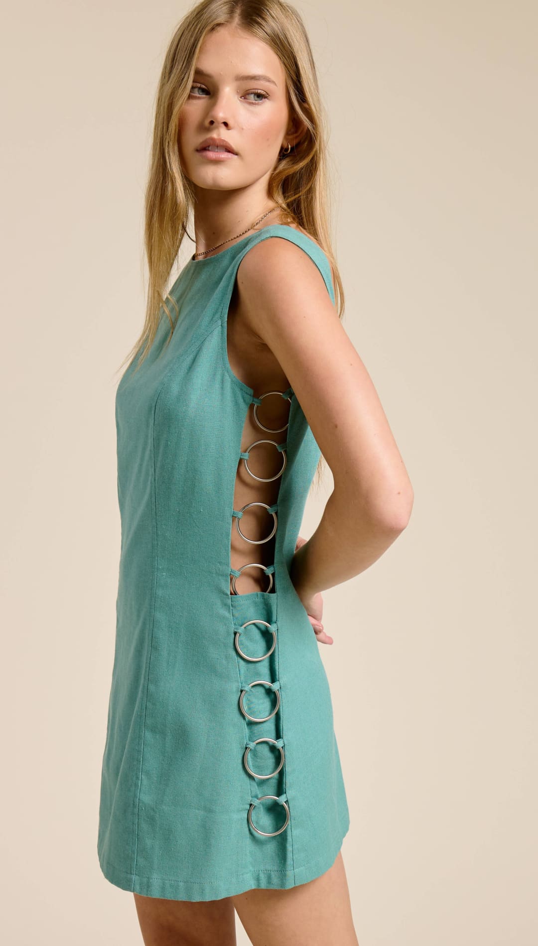 Teal sleeveless mini dress with a back panel featuring vertical metal rings.