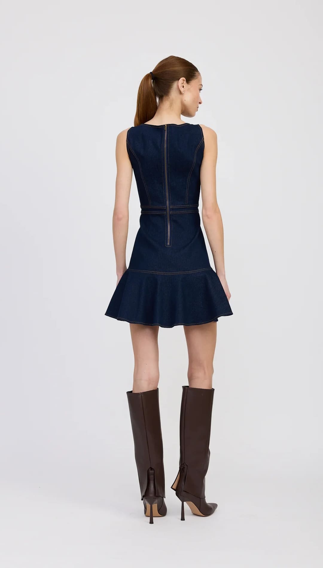 Sleeveless dark blue denim mini dress with a ruffled hem and a back zipper closure.