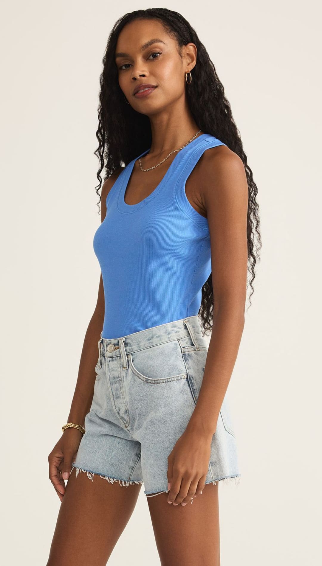 Woman in blue ribbed tank top and denim shorts.