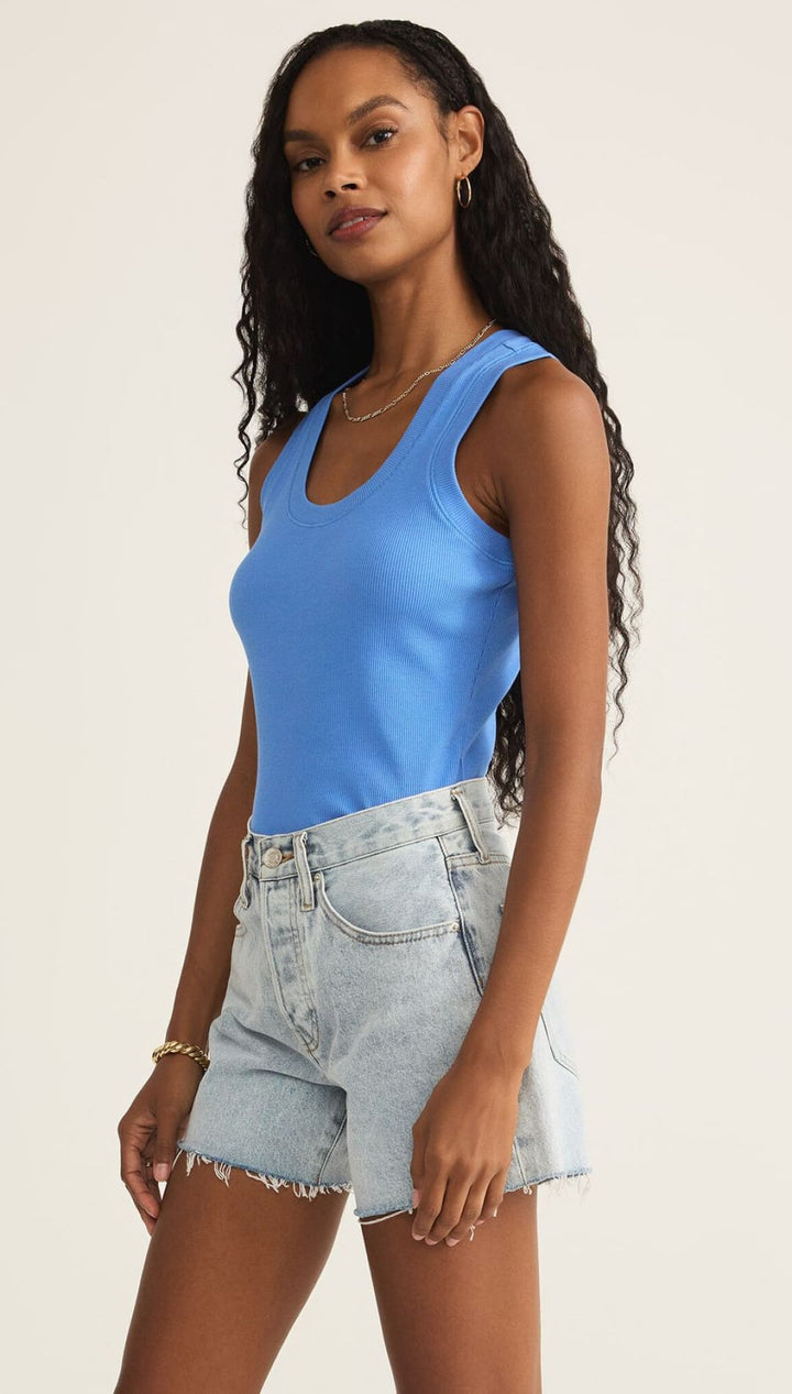 Woman in blue ribbed tank top and denim shorts.