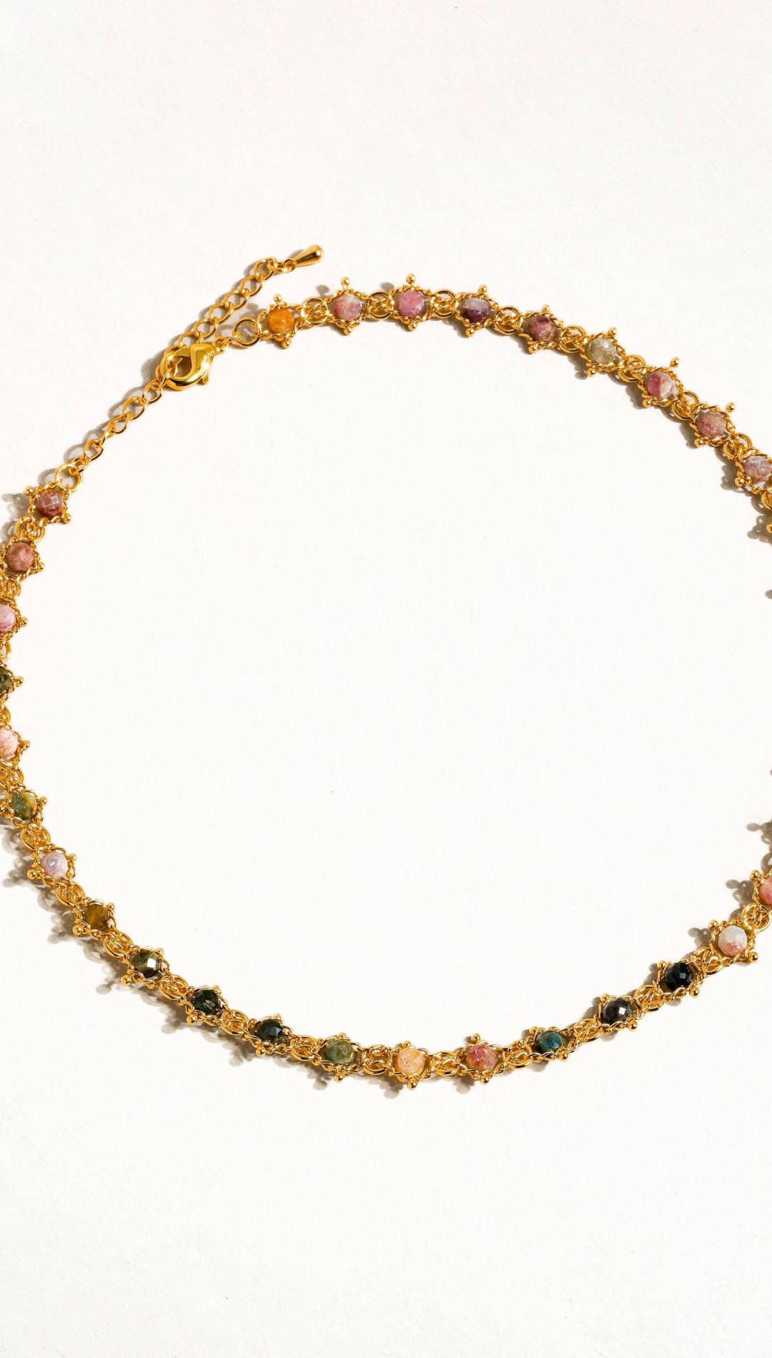 A delicate gold-toned necklace featuring a series of colorful, faceted gemstones set in intricate star-shaped metalwork.