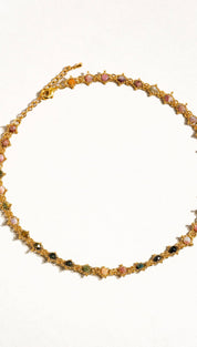 A delicate gold-toned necklace featuring a series of colorful, faceted gemstones set in intricate star-shaped metalwork.