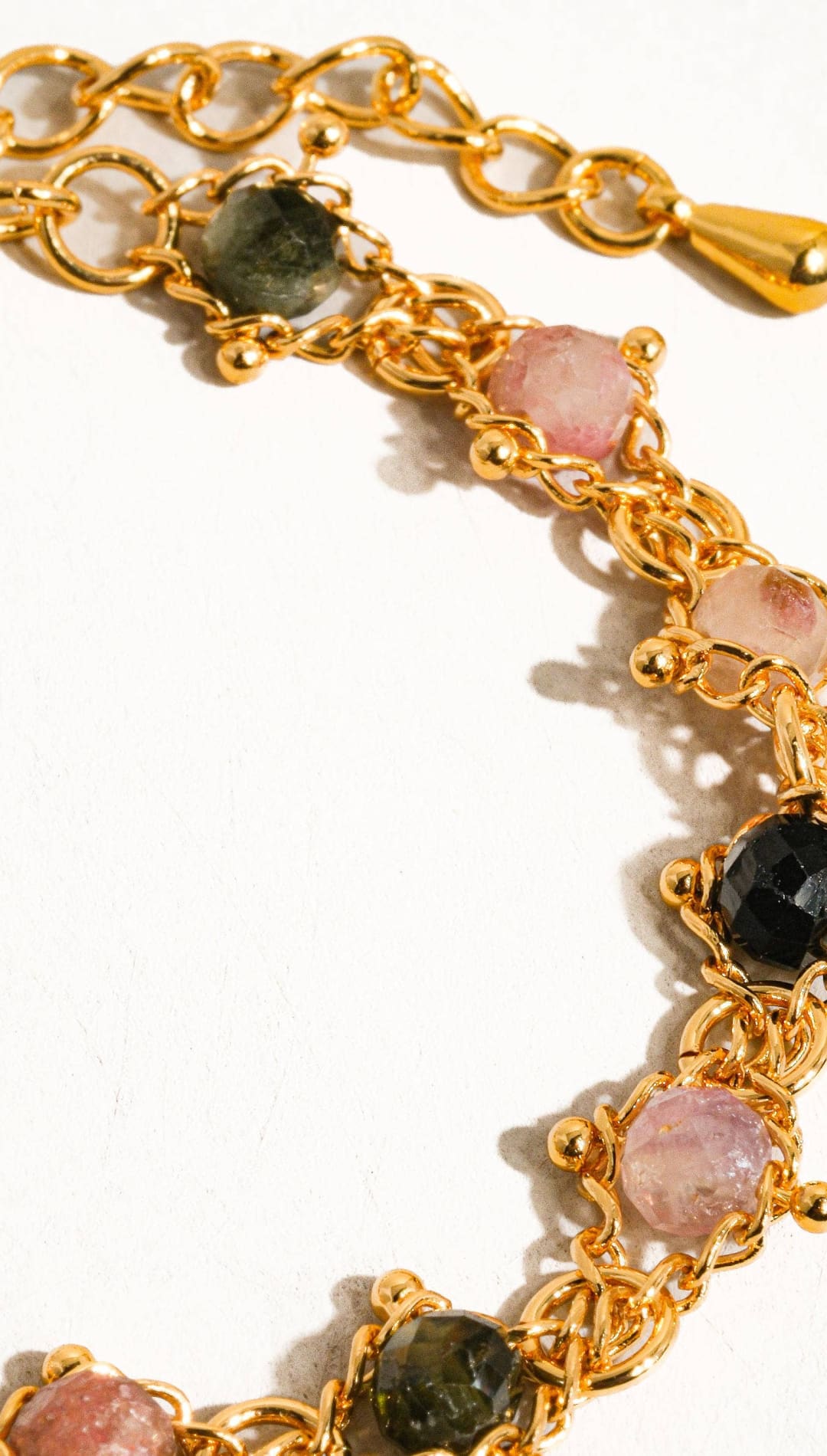Gold-toned chain bracelet adorned with faceted pink, green, and black tourmaline stones.