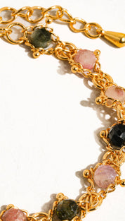 Gold-toned chain bracelet adorned with faceted pink, green, and black tourmaline stones.