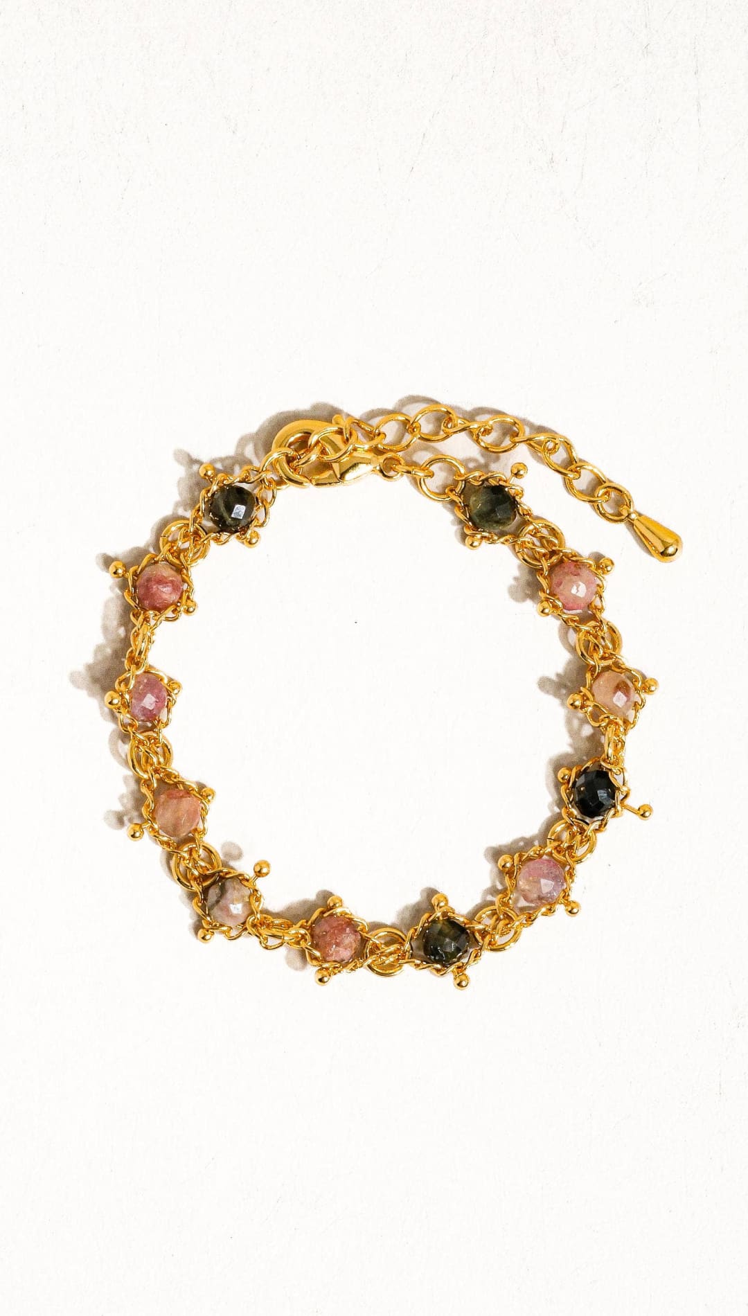 Gold-toned bracelet featuring alternating pink and dark green faceted gemstones set in a delicate chain design.