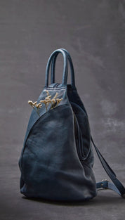 Dark blue leather backpack with a soft, slightly wrinkled texture and minimalist design.