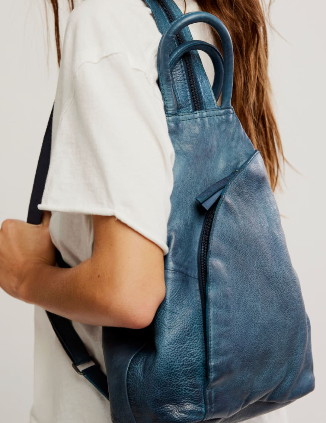 A teal leather backpack with a soft, slightly distressed texture and rounded top handles.