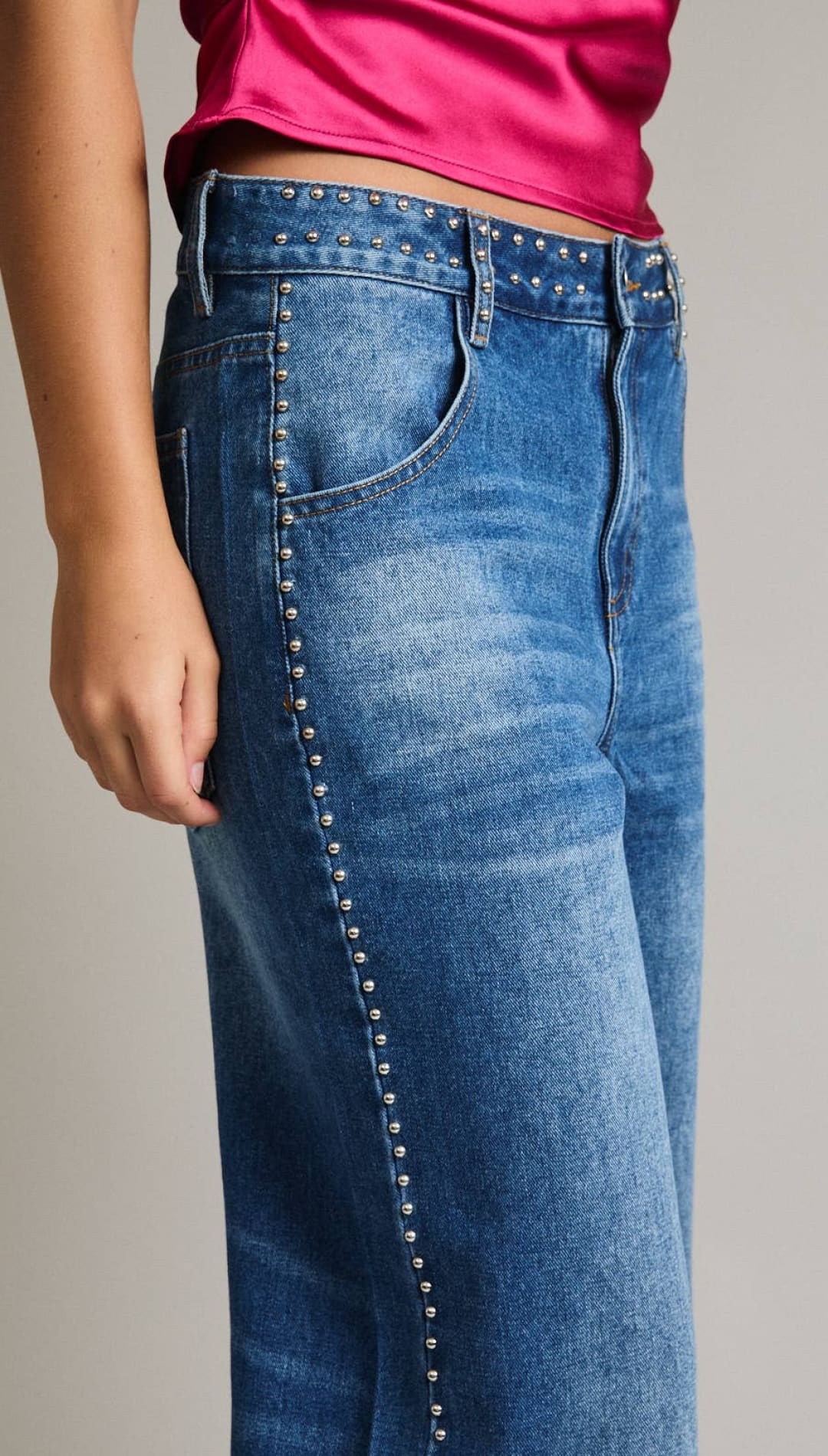 Blue denim jeans with silver studs along the side seam.