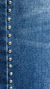 Blue denim fabric with a vertical line of silver-toned metal studs.