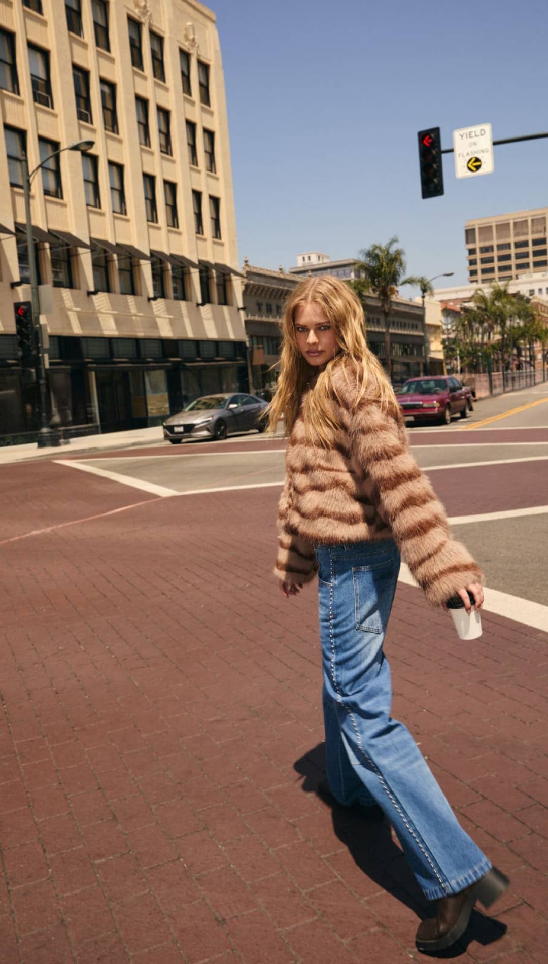 A woman wearing a fluffy, striped brown and beige faux fur cropped jacket with long sleeves.