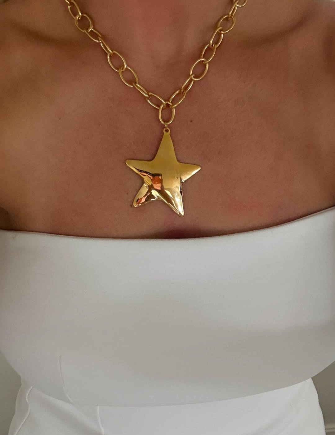 Gold chain necklace with a dangling, textured star pendant.