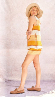 A woman wears a sleeveless, tiered knit dress with horizontal stripes of mustard yellow and cream.