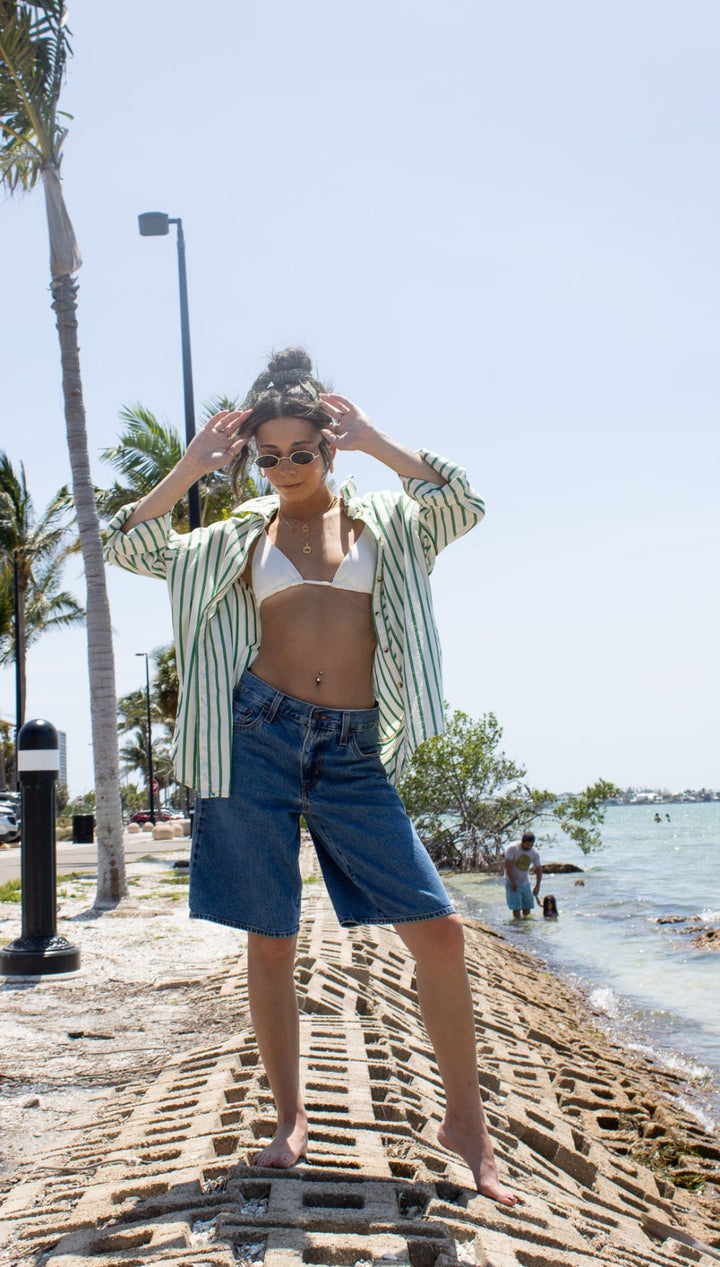 Woman in denim shorts and striped shirt.