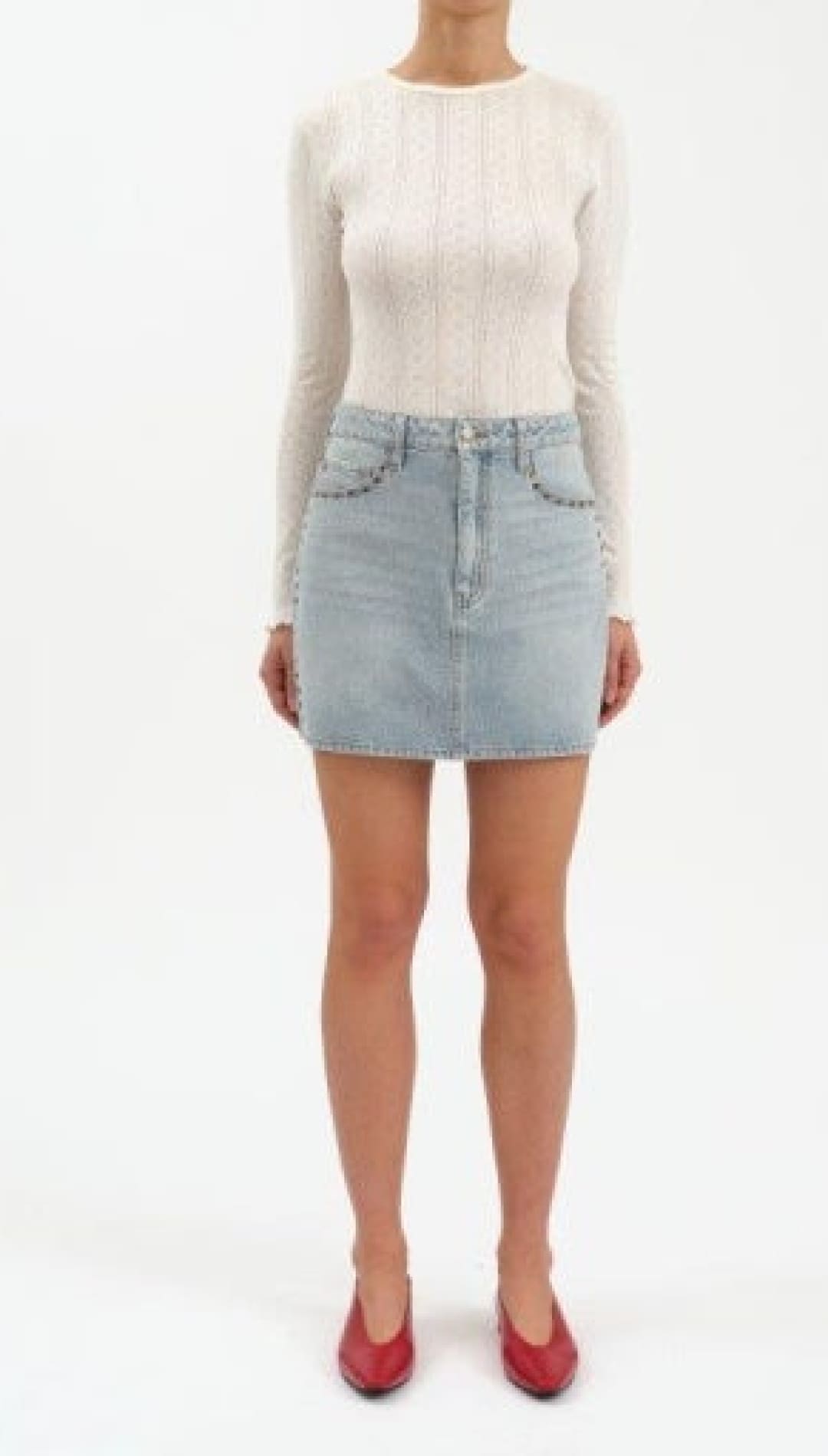A light blue denim mini skirt with front pockets adorned with small silver studs, and a zipper fly closure.