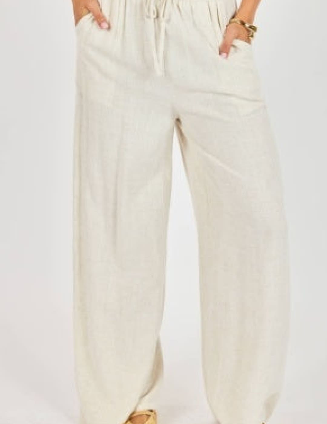 Cream-colored, loose-fitting wide-leg pants with a drawstring waist and side pockets.