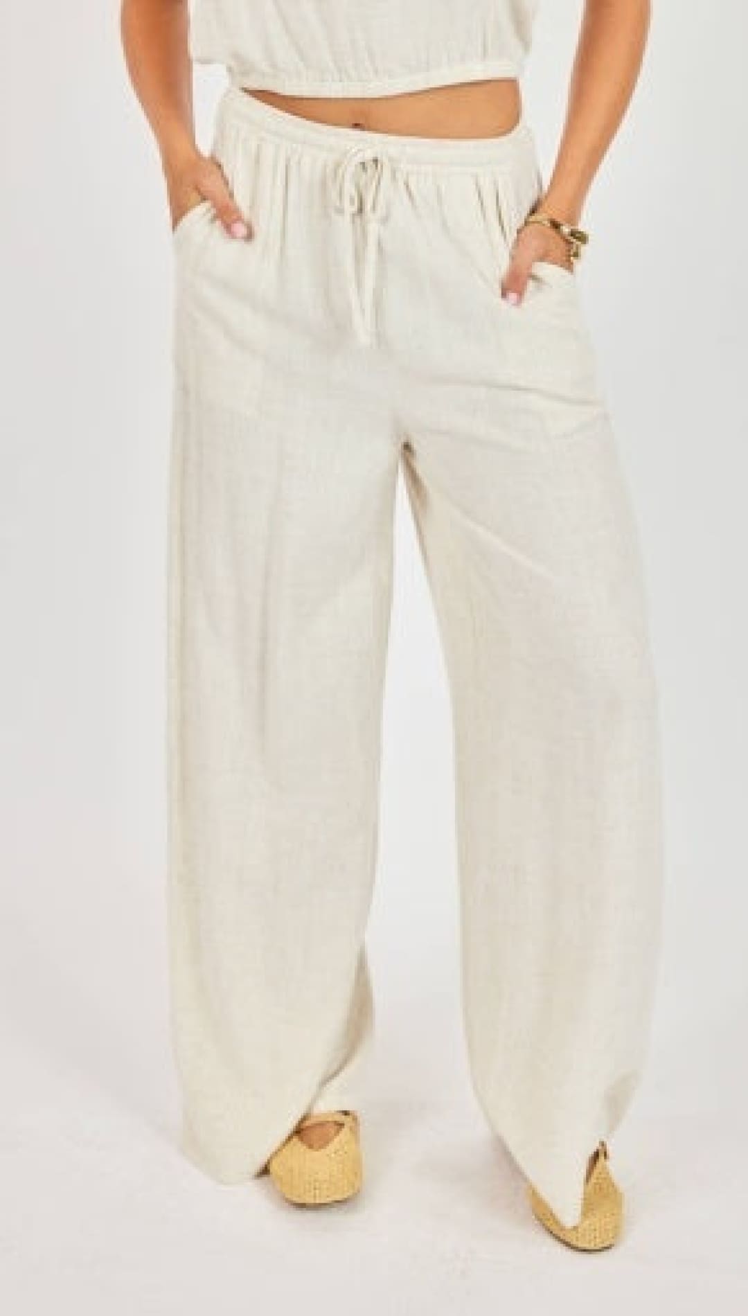 Cream-colored, loose-fitting wide-leg pants with a drawstring waist and side pockets.