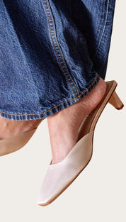 Beige pointed-toe heeled mules.